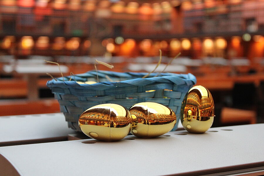 Ein Osterkorb mit 3 goldenen Ostereiern, welche vor dem Korb liegen.