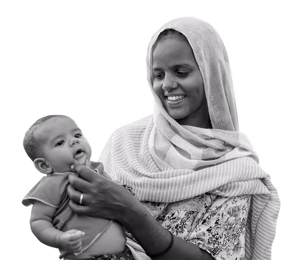 Smiling woman wearing a headscarf holding and looking at a baby.